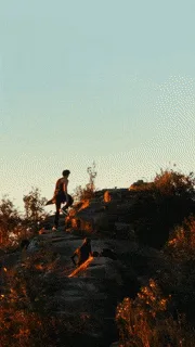 A six-panel image sequence shows a person hiking up a rocky hillside at sunset, progressively revealing more of the urban…