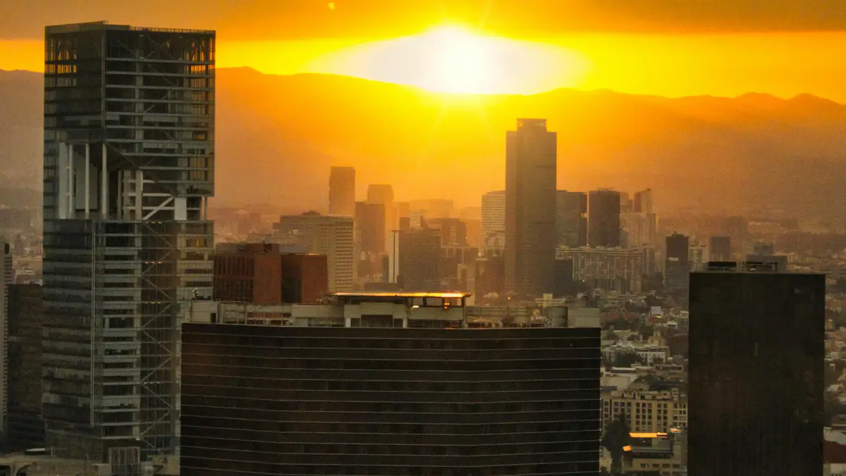 Vibrant golden hues illuminate the Mexico City skyline, modern skyscrapers rising like giants from the urban sprawl, as a…