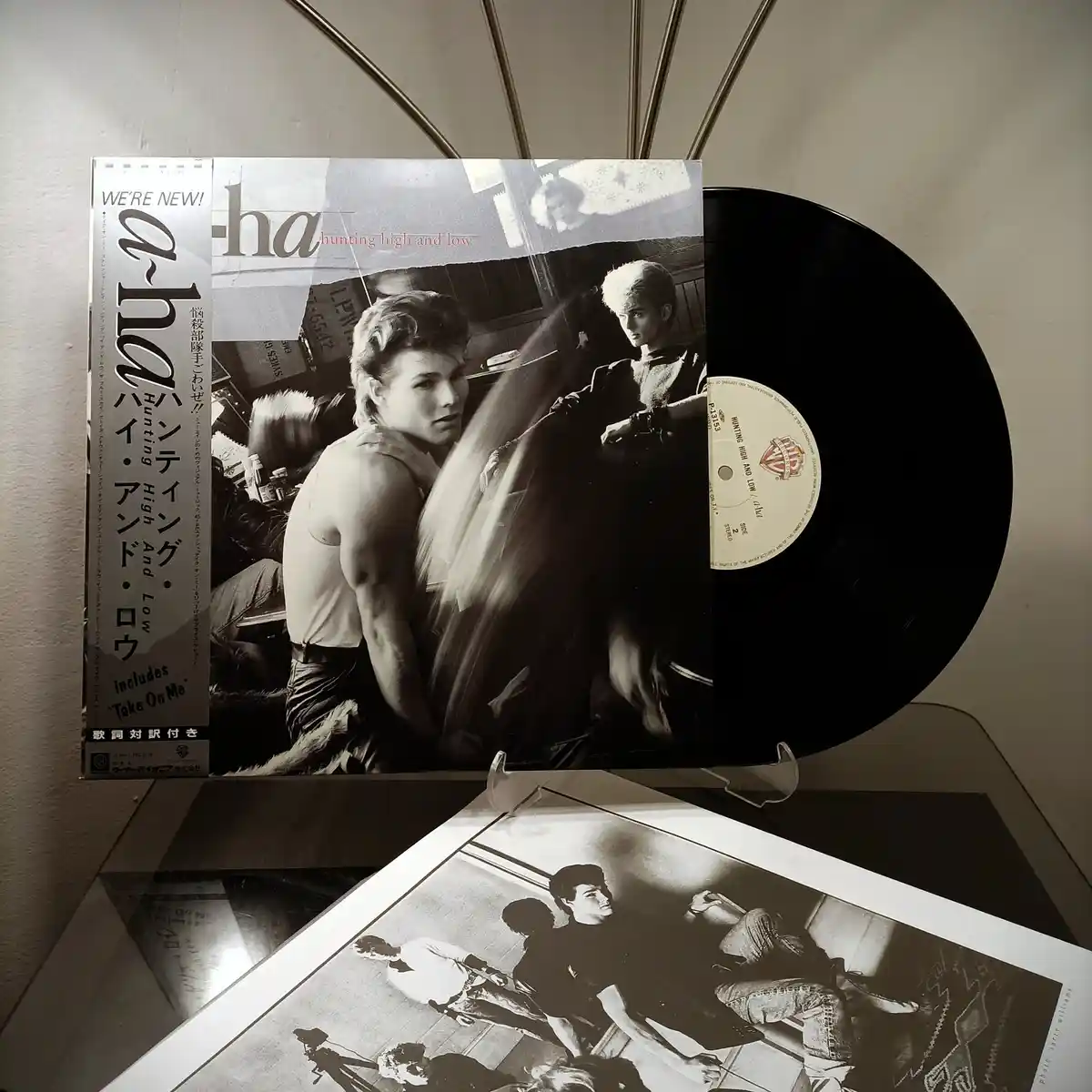 A black-and-white photo shows a vinyl record of a-ha's 'Hunting High and Low' album partially pulled from its Japanese…
