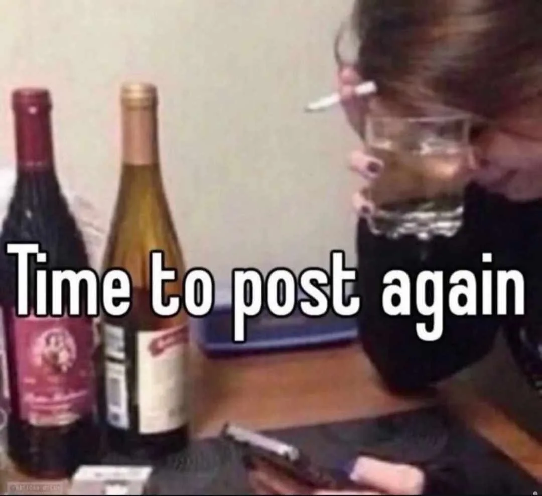 A person with dark hair and glasses, holding a cigarette in one hand and a glass of clear liquid in the other, leans over a…