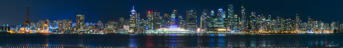 A panoramic night photograph of a brightly lit city skyline, likely Vancouver, with numerous skyscrapers and waterfront…