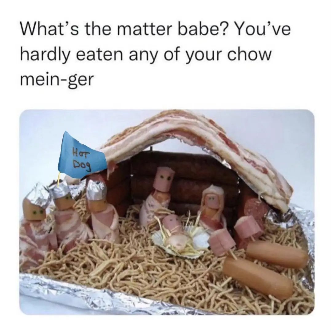 A food art nativity scene made from hot dogs, bacon, and chow mein noodles, with a small blue flag reading 'HOT DOG' stuck…