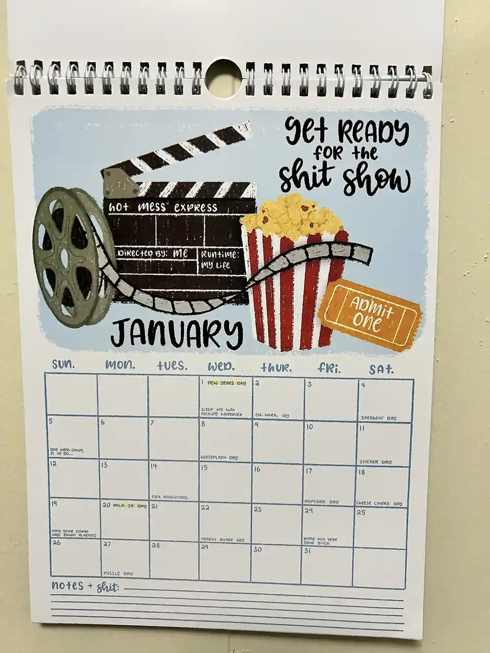 A January calendar page with a movie theme, featuring a clapperboard labeled 'hot mess express' with 'Directed by: Me' and…