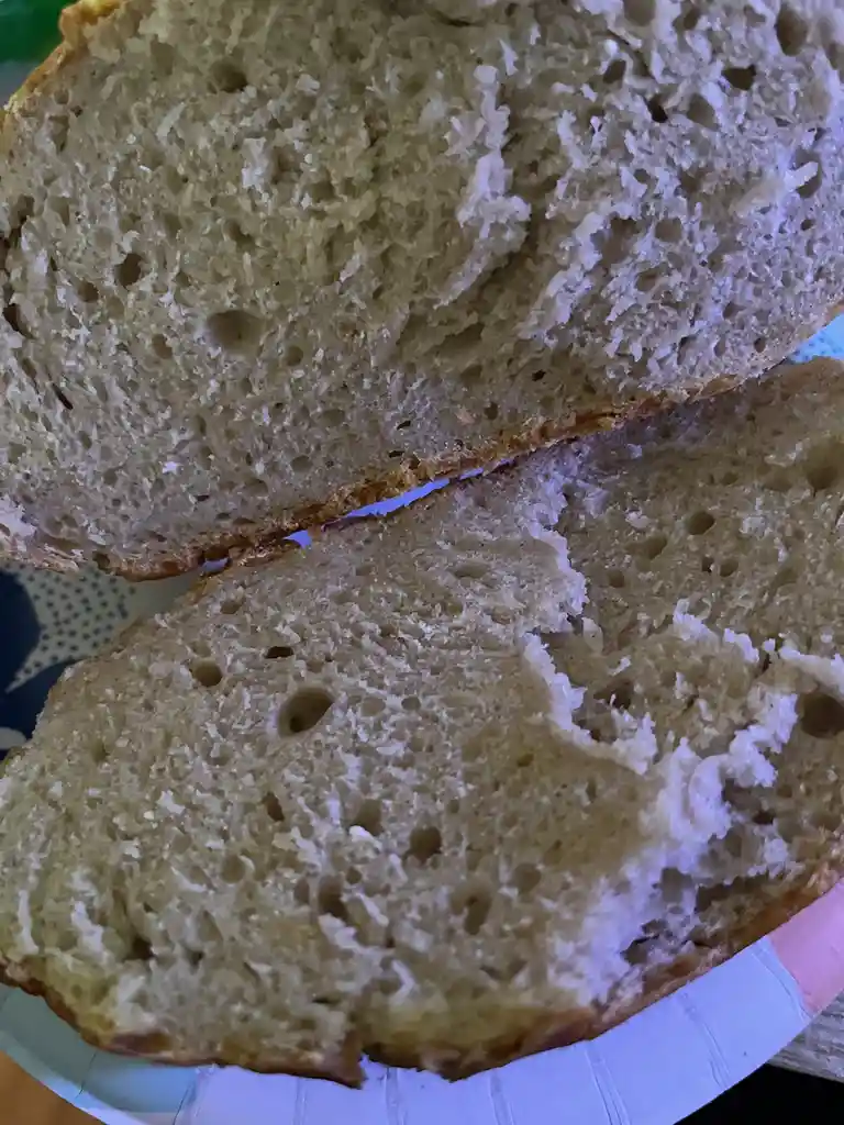 A close-up photo shows two halves of a freshly baked loaf of bread, revealing its airy, porous crumb structure with a…