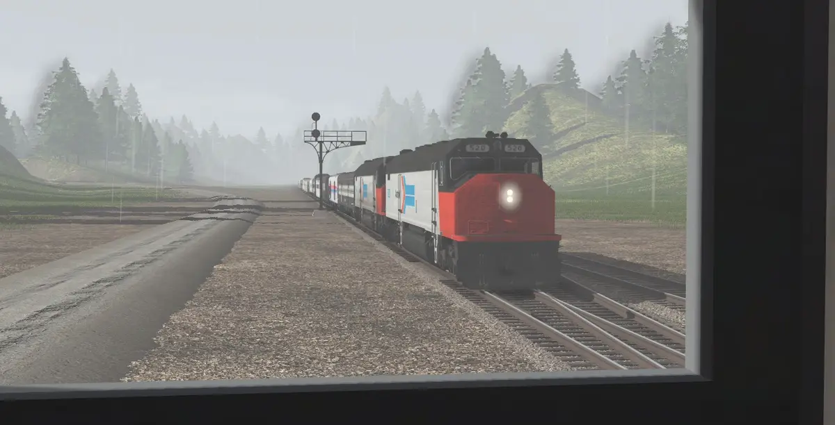 A train with a red and white locomotive numbered 520 is seen approaching on a rainy day through a window, with trees and…