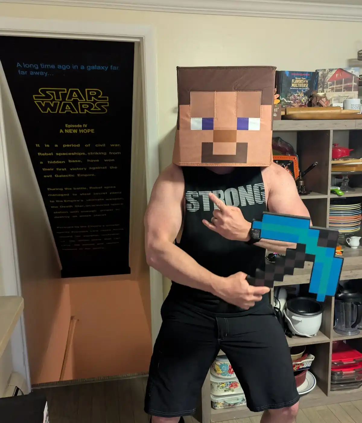 A muscular man wearing a pixelated Minecraft Steve head and holding a pixelated diamond sword points to his chest while…