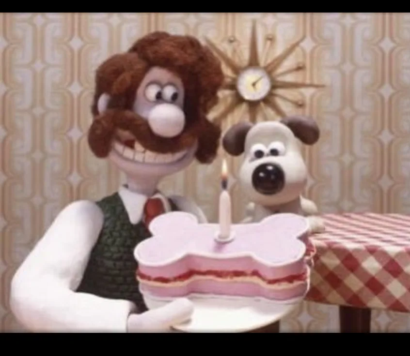 A still from the Wallace and Gromit animated film shows Wallace, a man with brown hair and a mustache, holding a bone-shaped…