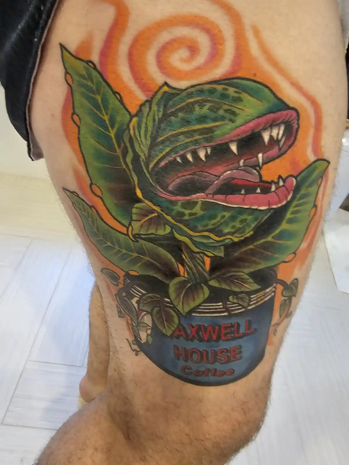 A tattoo on a person's leg depicts a carnivorous plant with sharp teeth and an open mouth, resembling a Venus flytrap…