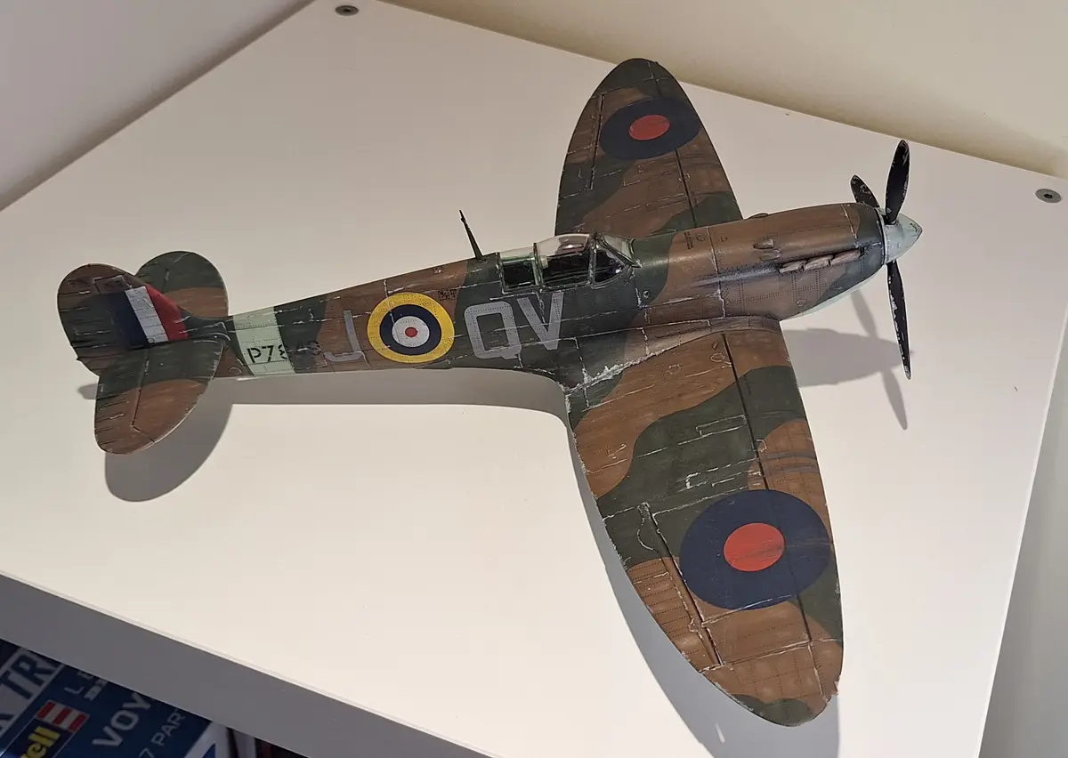 A detailed model of a World War II-era British fighter plane, likely a Supermarine Spitfire, with authentic camouflage…
