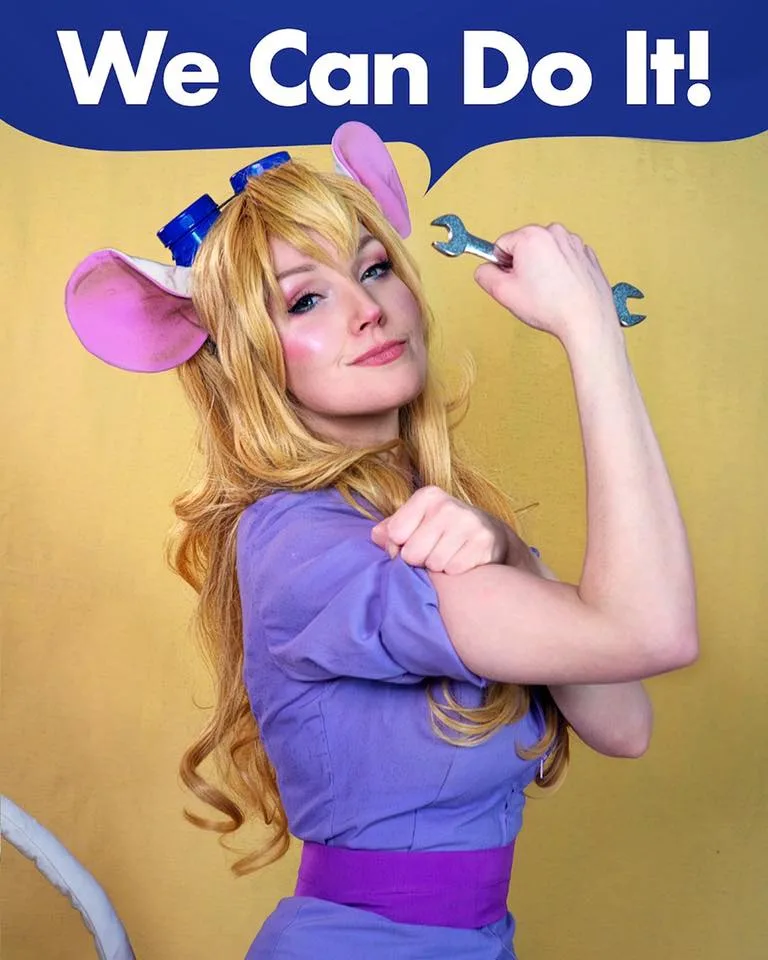 A woman with long blonde hair, wearing a purple outfit and large pink mouse ears with blue bows, poses confidently with her…