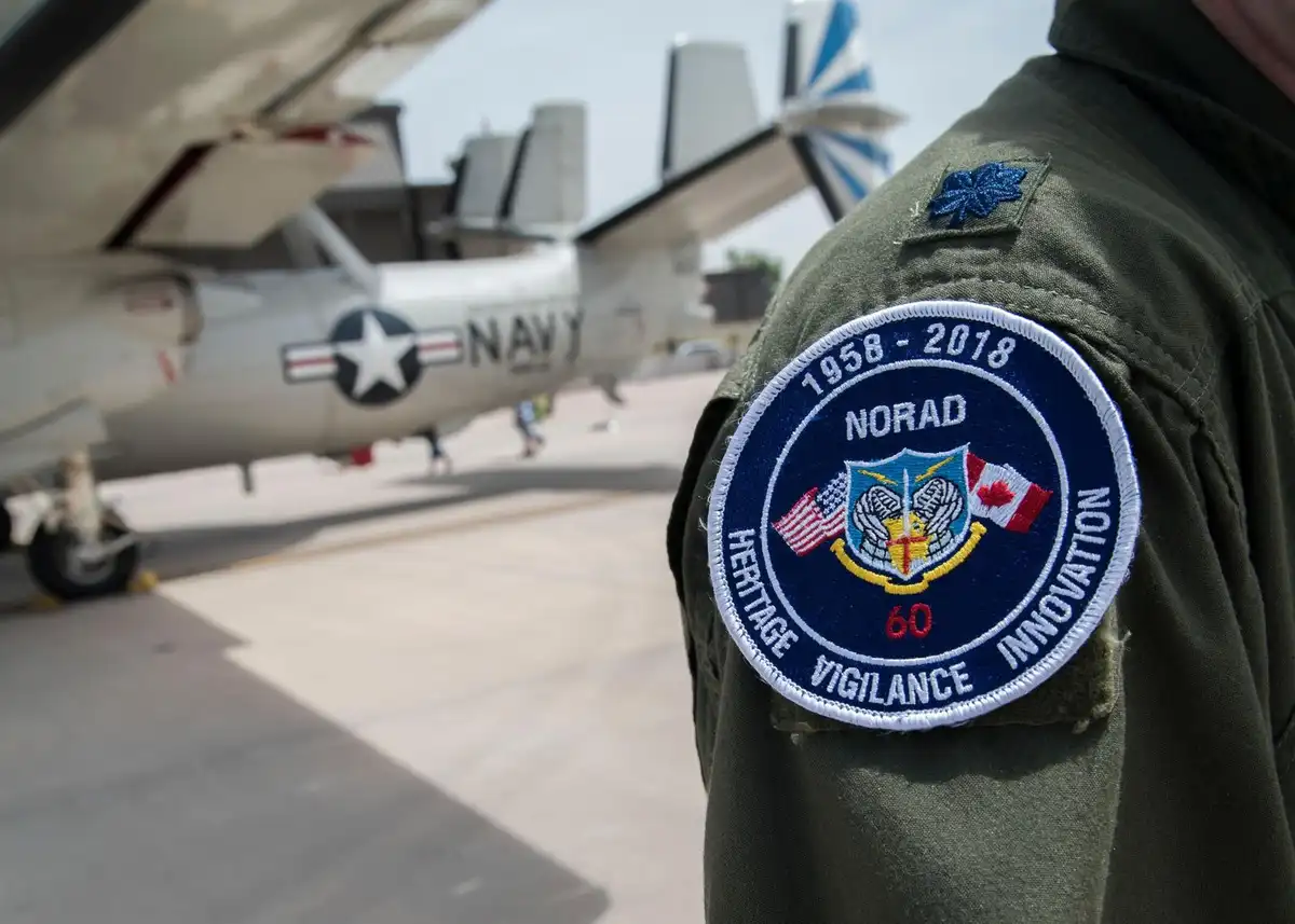 A close-up of a military uniform sleeve featuring a NORAD 60th anniversary patch (1958-2018) with the words 'Heritage…