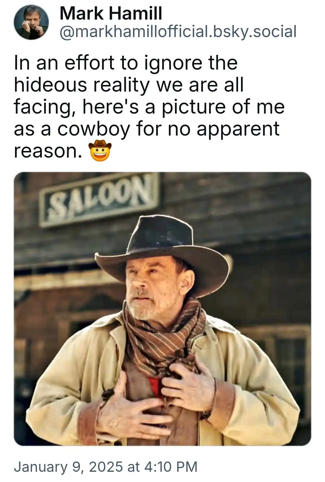 An image of actor Mark Hamill dressed as a cowboy, wearing a wide-brimmed hat, a beige jacket, and a patterned scarf…