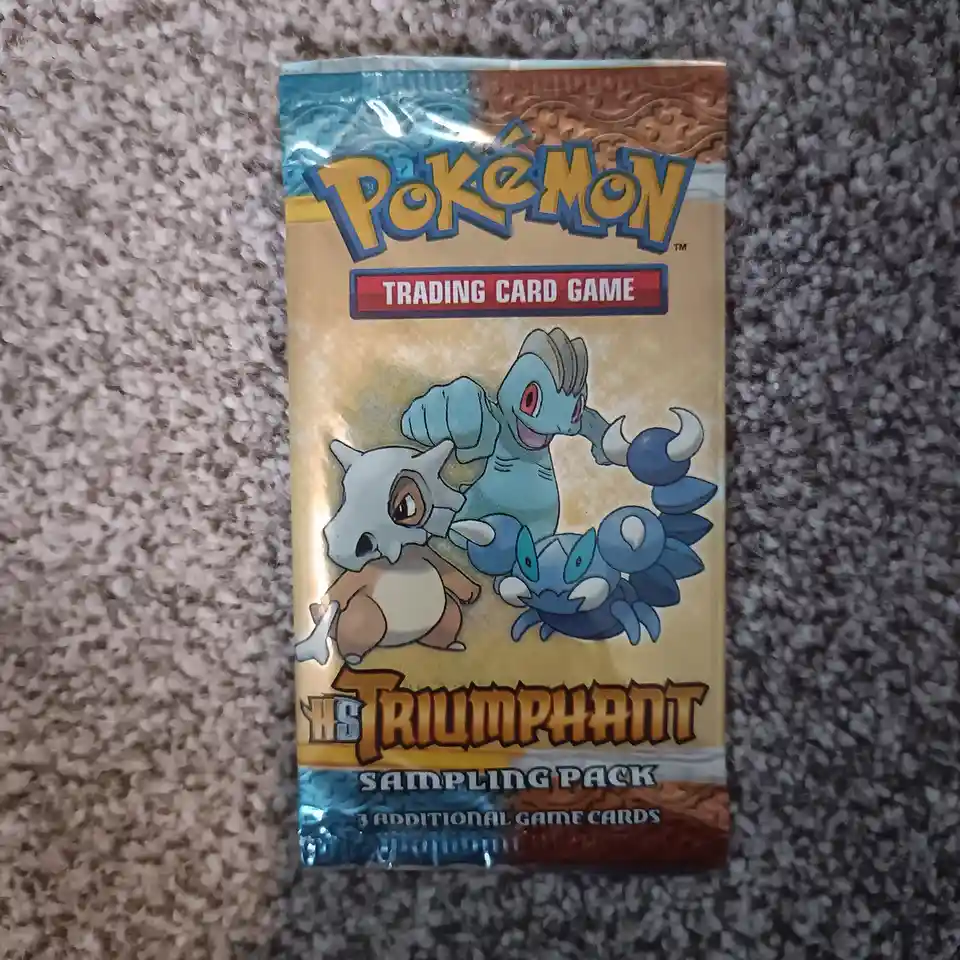 A sealed Pokémon Trading Card Game sampling pack from the 'Triumphant' expansion, featuring artwork of the Pokémon…