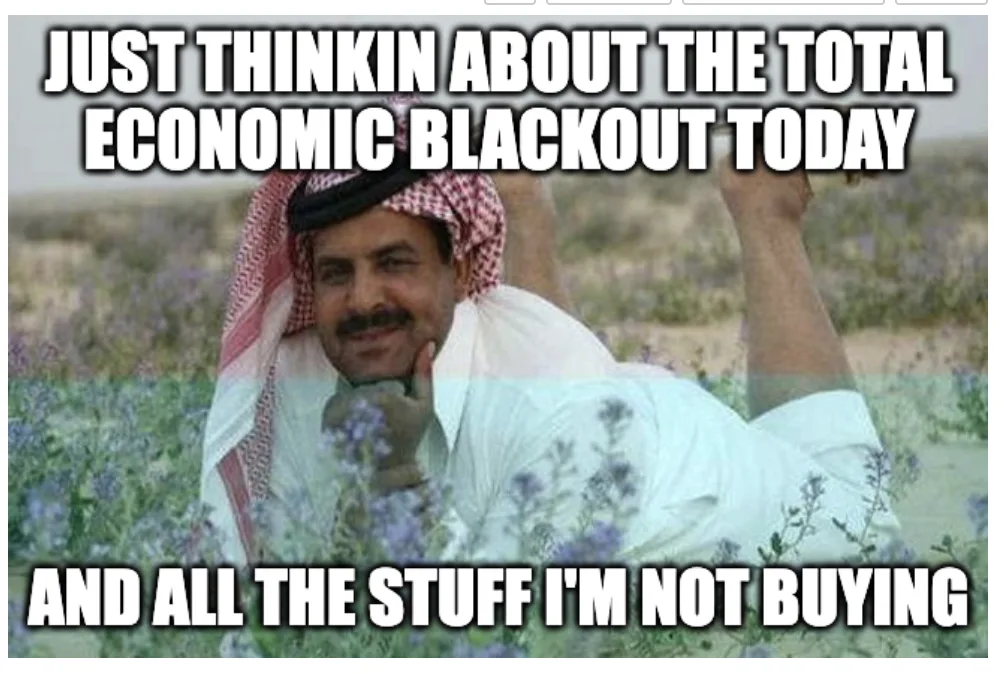 A man wearing a red-and-white checkered keffiyeh and white thobe lies in a field of purple flowers, smiling smugly with his…