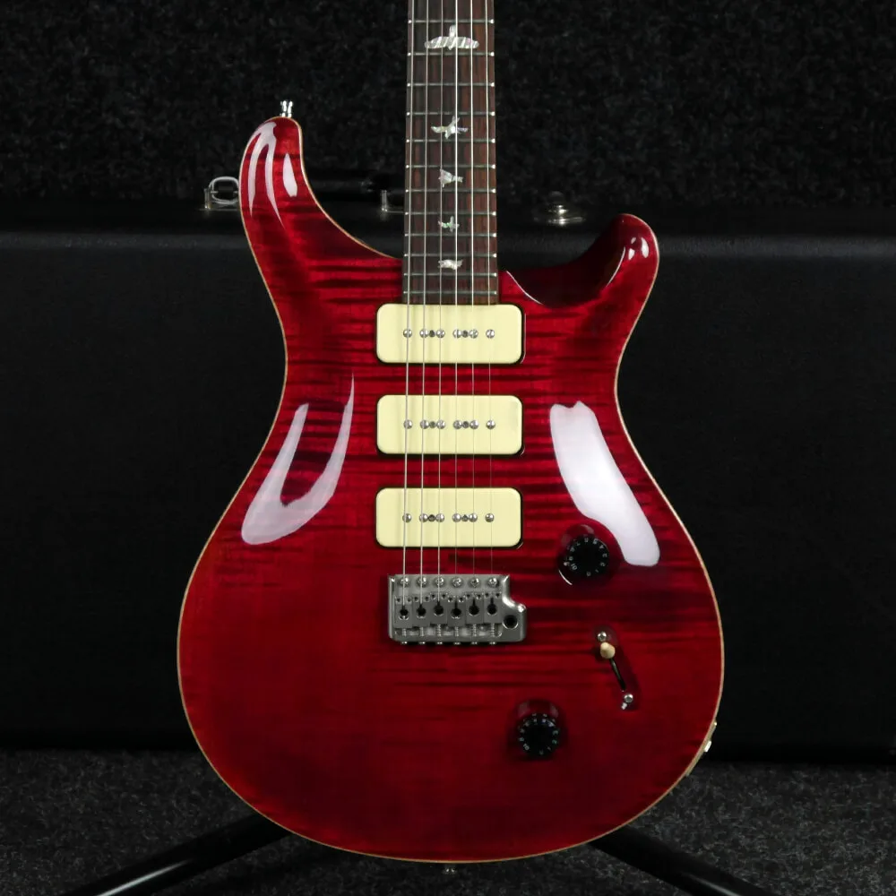 a glossy red electric guitar with a visible wood grain finish, three cream-colored pickups, and a black background, overlaid…