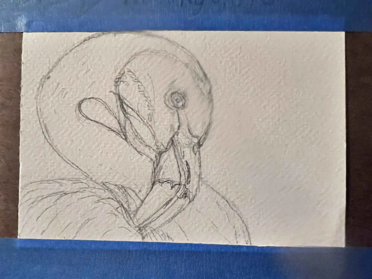 A rough pencil sketch on textured paper depicts a distorted, abstract humanoid figure with a large circular head, one eye…