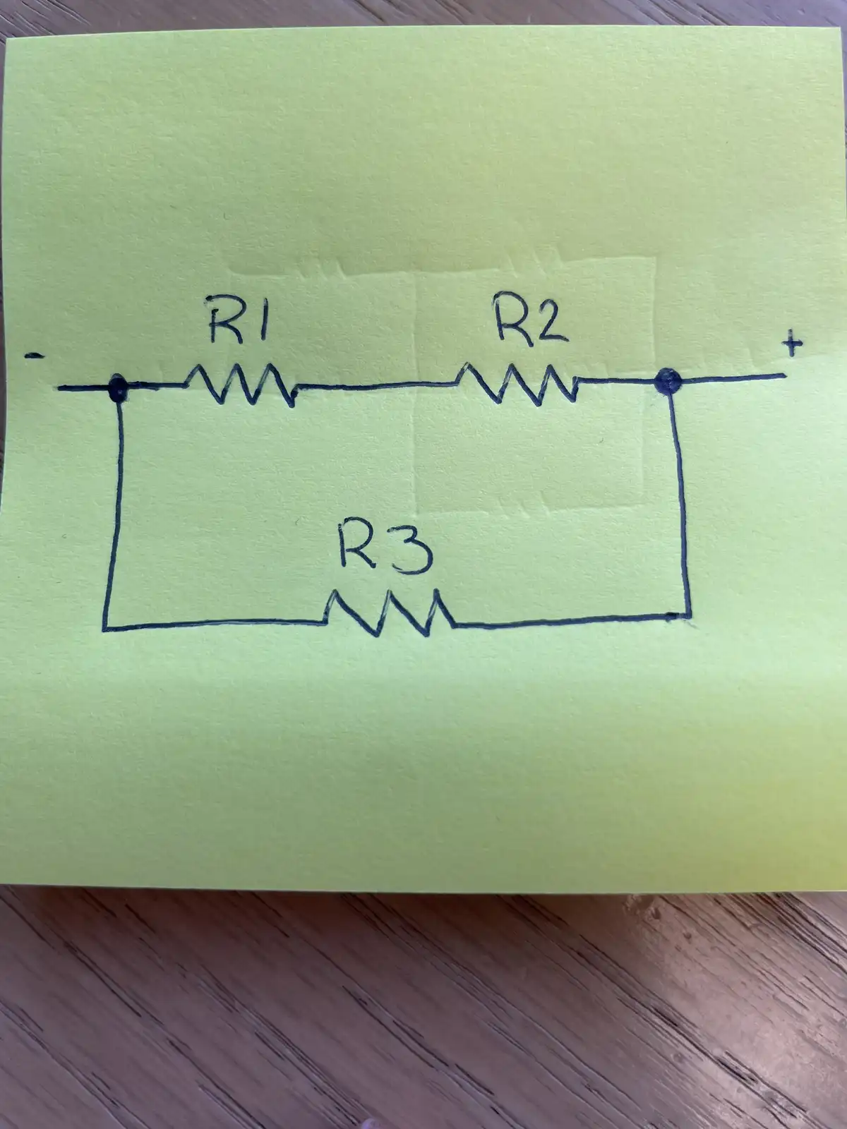 A hand-drawn electrical circuit on a yellow sticky note shows three resistors labeled R1, R2, and R3 connected in parallel…