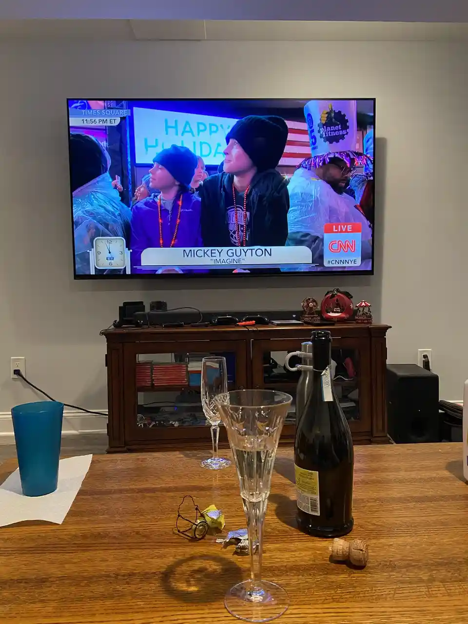 A TV screen shows a CNN broadcast from Times Square at 11:56 PM ET, featuring country singer Mickey Guyton performing…