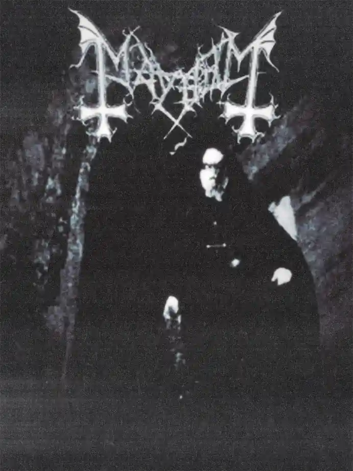 A grainy black-and-white photo shows a man in a dark coat seated, with the word 'MAYHEM' in a stylized, spiky, gothic font…