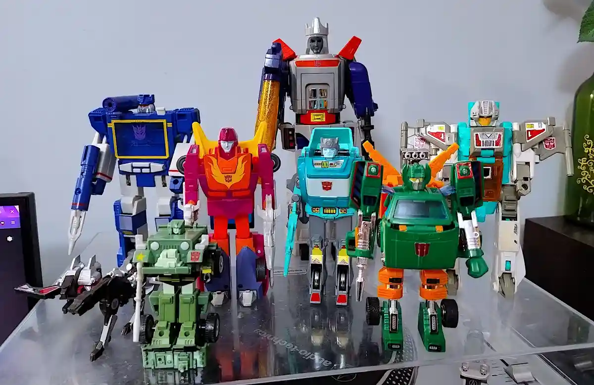 A collection of colorful Transformers action figures, including Optimus Prime and other Autobots, are arranged in a row on a…
