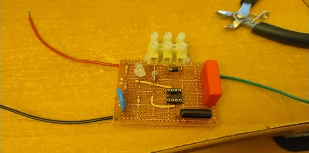 A simple electronic circuit built on a breadboard with wires, resistors, a red push-button switch, a small LED, and terminal…