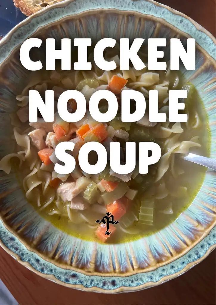 A close-up photo of a bowl of chicken noodle soup with visible noodles, chicken pieces, carrots, and celery in a light…