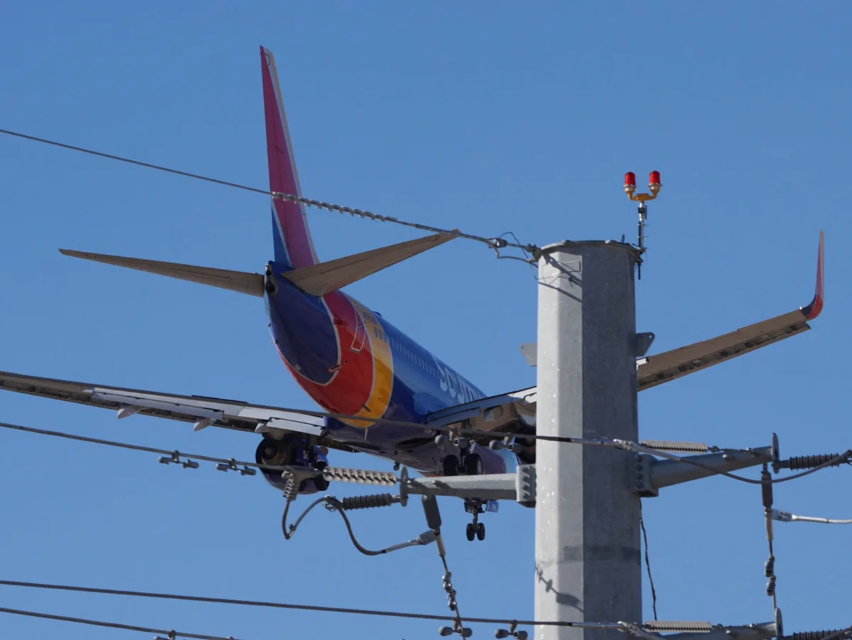 A Southwest Airlines plane is humorously edited to appear as if it's perched atop a utility pole, with its wings and tail…