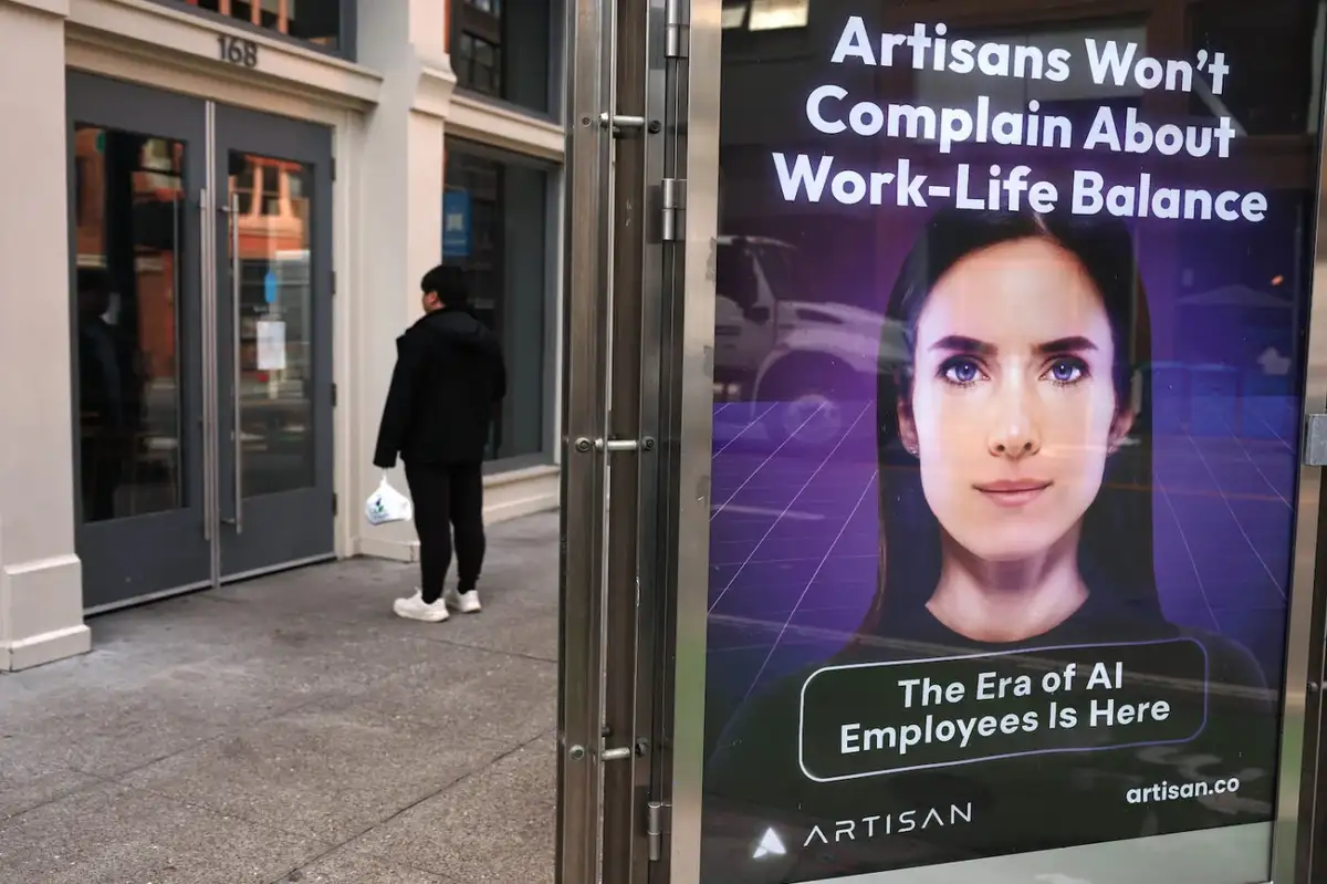 A person walks past a glass door displaying a large advertisement featuring a woman's face with the text 'Artisans Won't…
