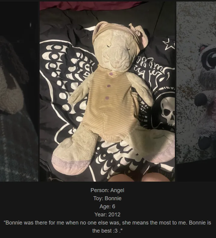 A worn, light-colored plush toy resembling a mouse or rat, wearing a beige onesie with purple buttons, lies on a black and…