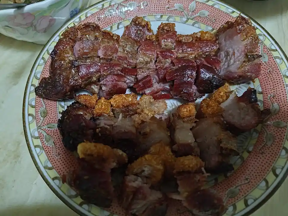 A plate filled with chopped, crispy-skinned roasted meat, likely pork belly or similar, arranged on a decorative plate with…