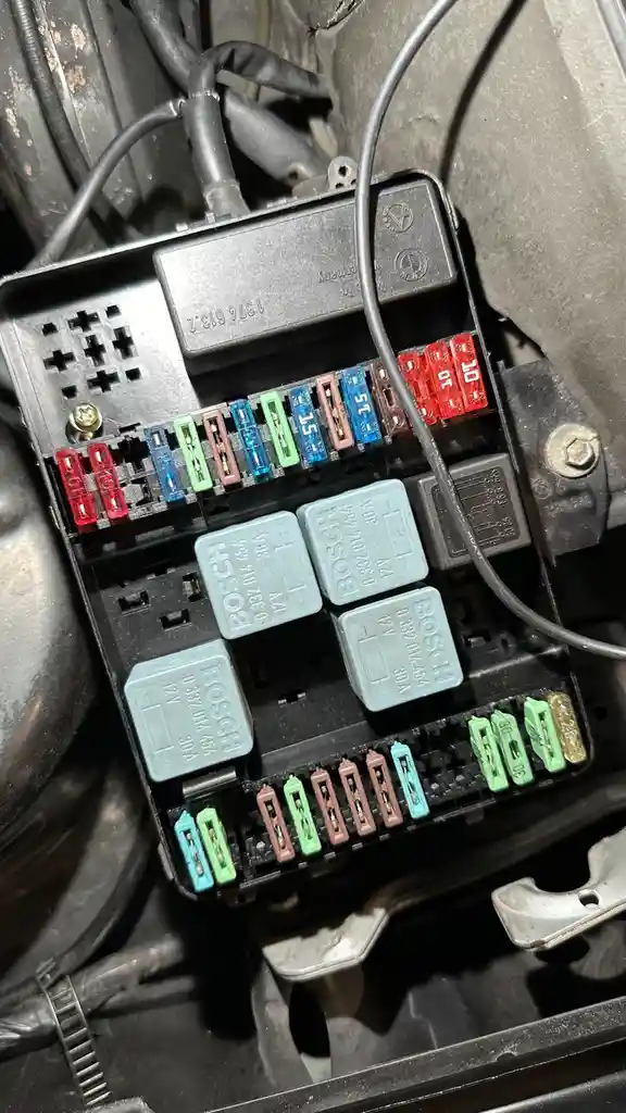 A close-up photo of a car's open fuse box showing various colored fuses and Bosch relays, with overlaid text reading 'i just…