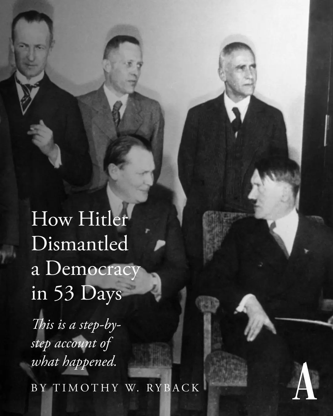 A black-and-white historical photo shows five men in suits, with Adolf Hitler seated on the right and another man seated to…