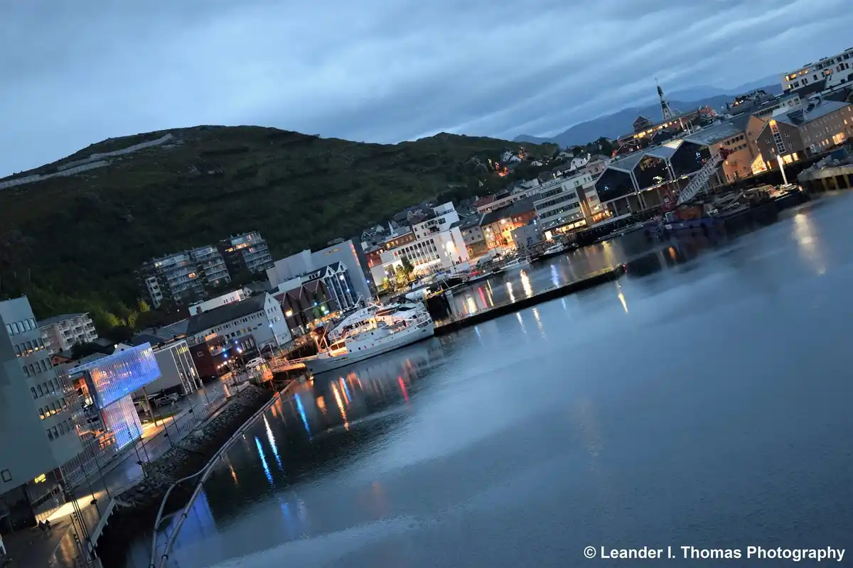 A scenic photo of a harbor town at dusk, with buildings, boats, and a hillside visible, overlaid with the text 'i'm not…