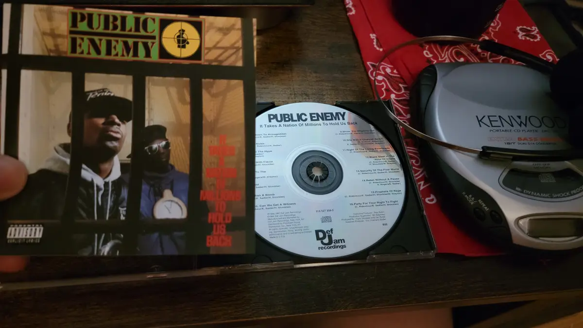 A photo shows a person holding open a CD case for Public Enemy's album 'It Takes A Nation Of Millions To Hold Us Back,' with…