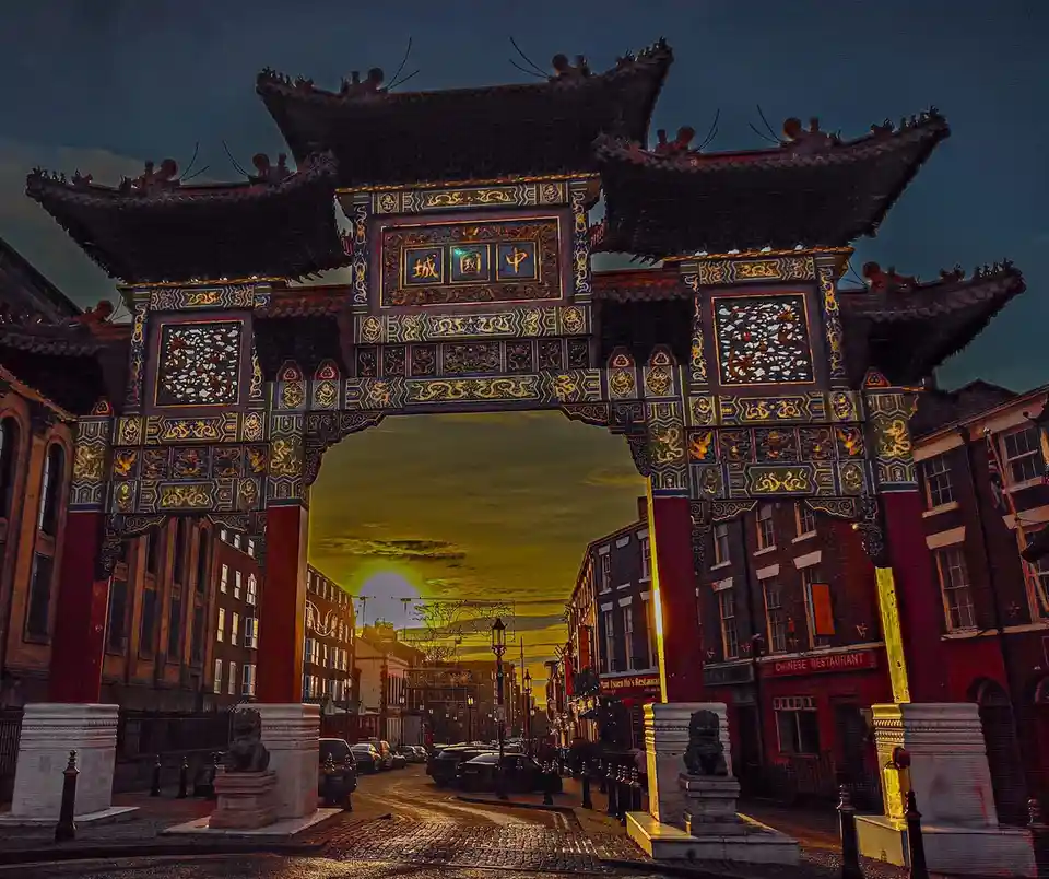 A grand, ornate Chinese archway with intricate gold and blue carvings and Chinese characters '中園城' on its central plaque…