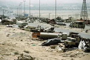a wide shot of a desolate, war-torn landscape filled with destroyed vehicles and debris under a hazy sky. The overlaid text…