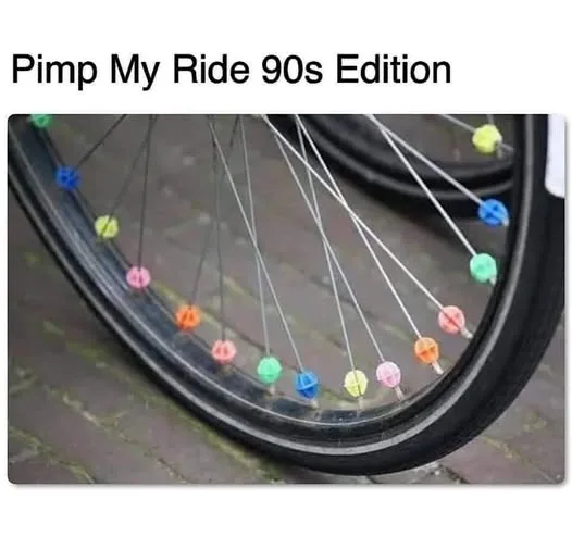 A close-up photo of a bicycle wheel with its spokes decorated by colorful, plastic, 90s-style hubcaps or spoke caps in…