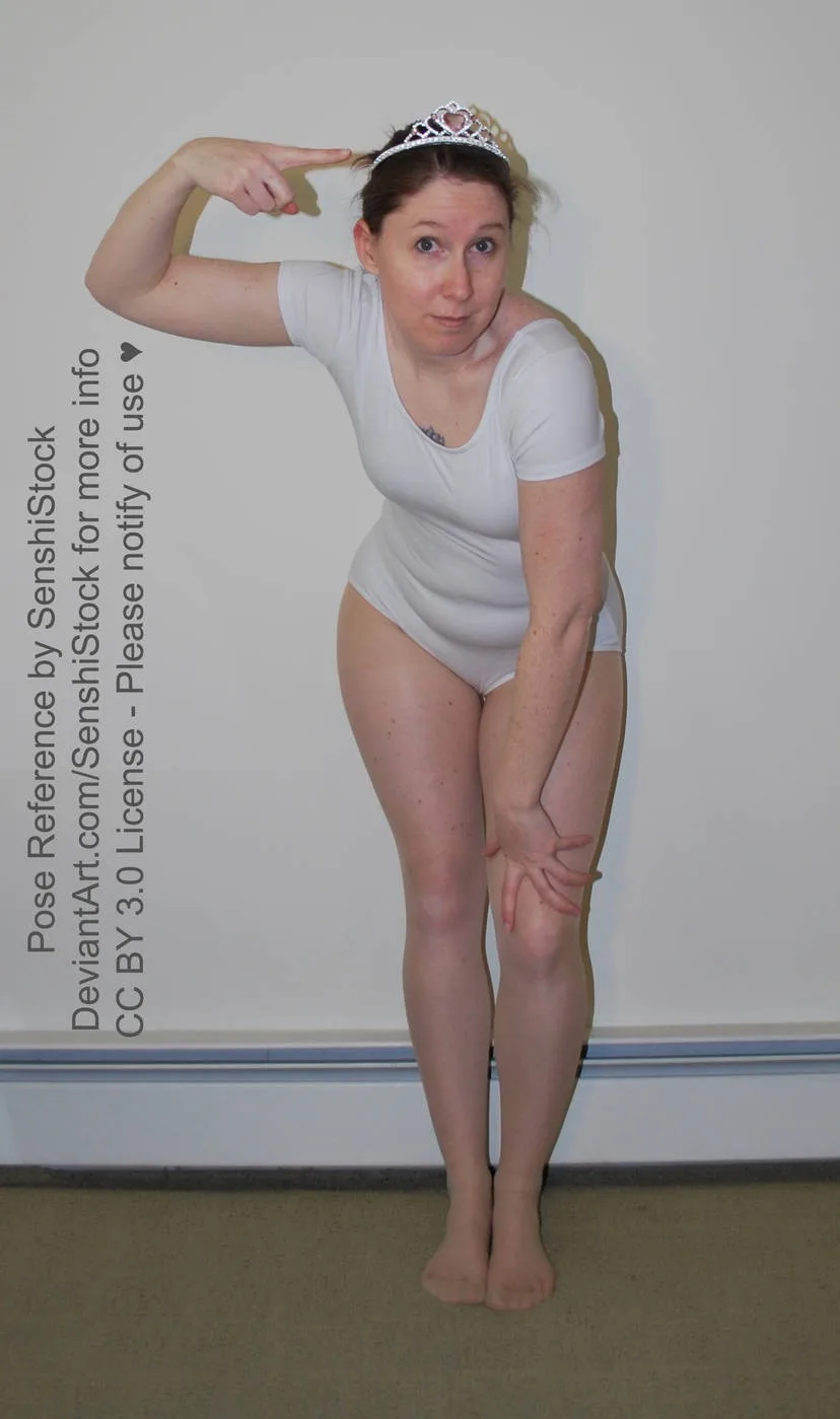 a woman in a white leotard and tiara poses with one hand pointing to her head and the other on her knee, looking directly at…