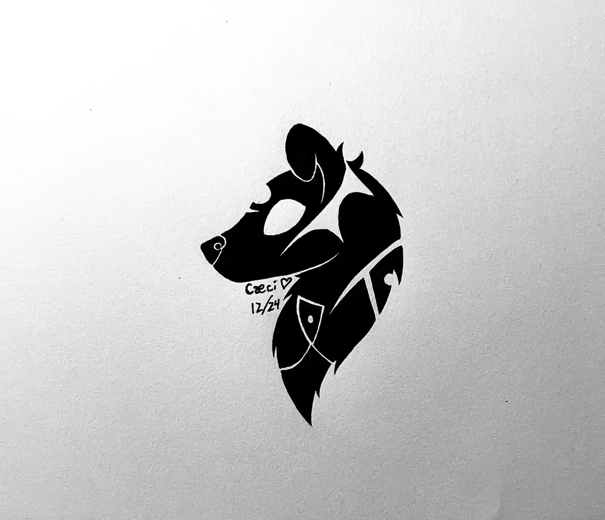 A black ink drawing on textured white paper shows a stylized animal head, possibly a wolf or dog, wearing a decorative…