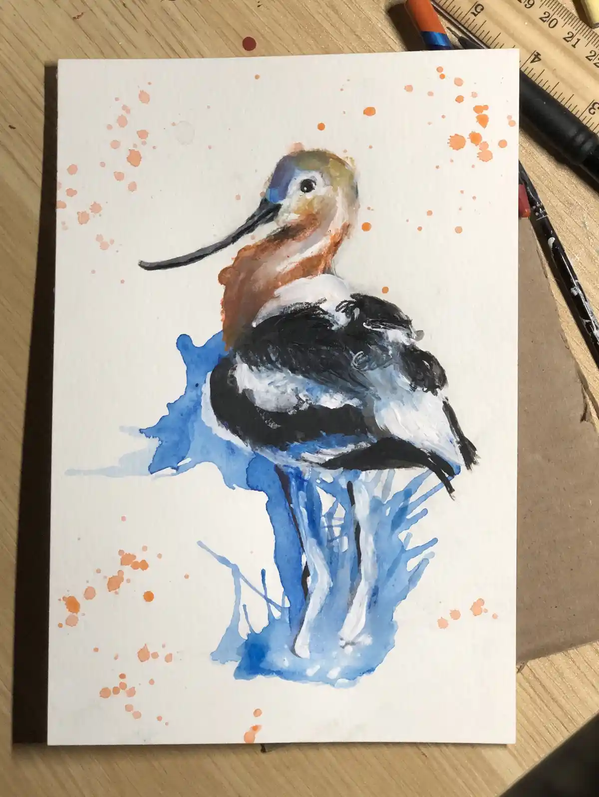 A watercolor painting of a bird with a long beak, brown and white plumage, and black wings, standing in blue water splashes…