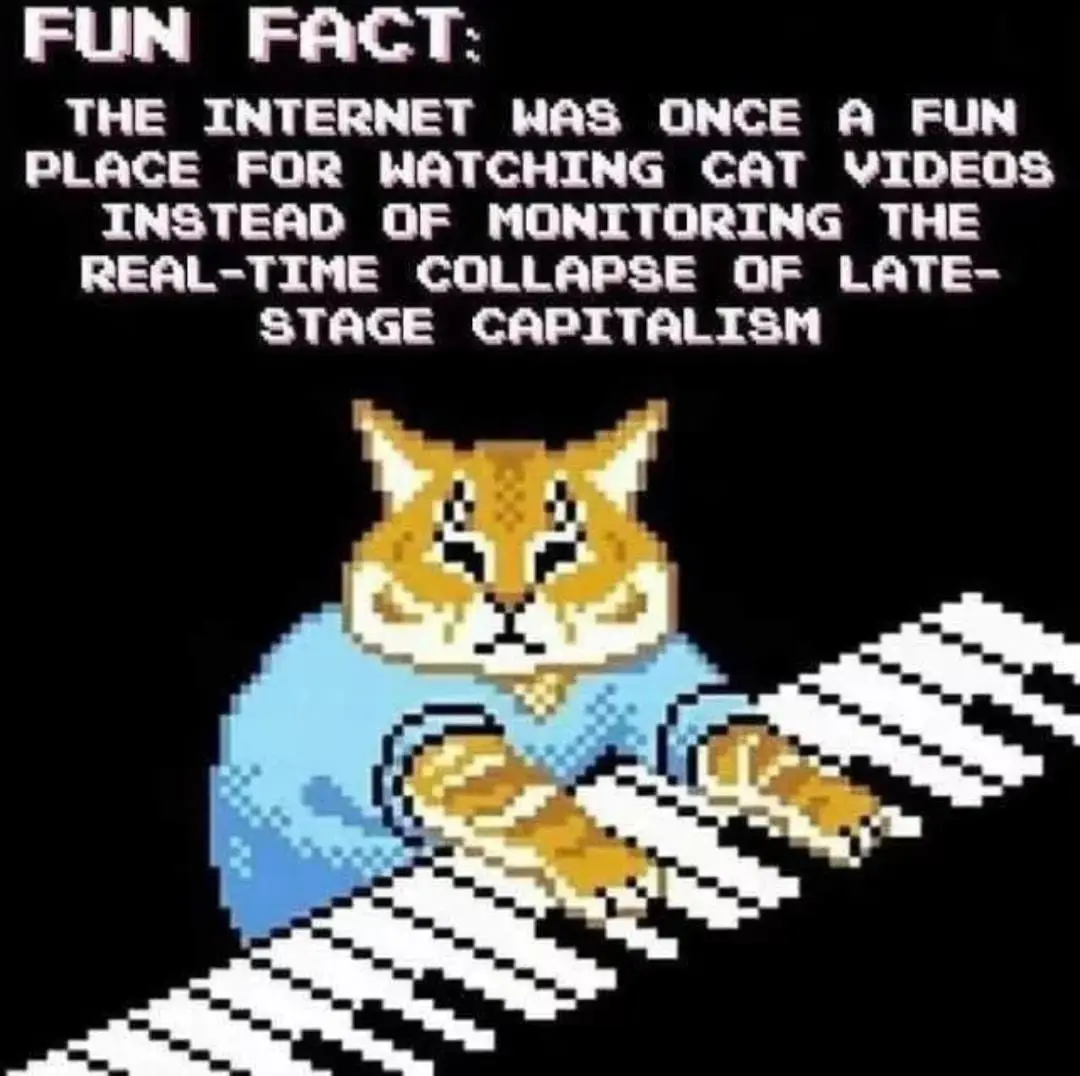 A pixelated image shows an orange cat wearing a blue shirt, sitting at a keyboard with white keys. Above the cat, white…