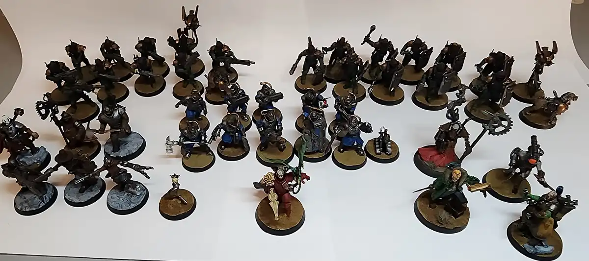 A large collection of painted fantasy and sci-fi miniatures arranged on a white surface, with one small, distinct miniature…