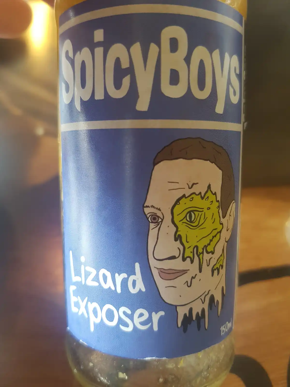A close-up of a bottle labeled 'SpicyBoys' with 'Lizard Exposer' written below. The label features a cartoon illustration of…