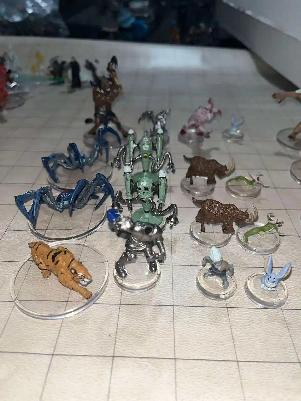 A collection of Dungeons & Dragons miniatures, including a green robot, blue spiders, a tiger, and various fantasy…