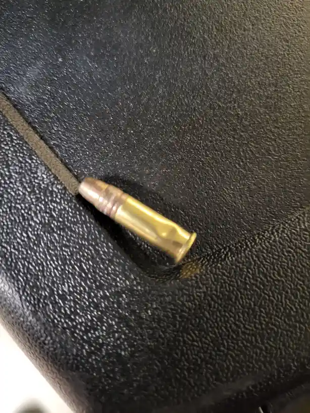 A single brass bullet casing lies on a textured black leather couch surface, near a seam. The overlaid text reads 'i found…