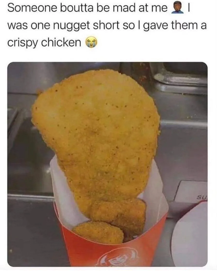 A close-up photo shows a large, oddly shaped fried chicken piece, resembling a giant nugget, standing upright in a red paper…