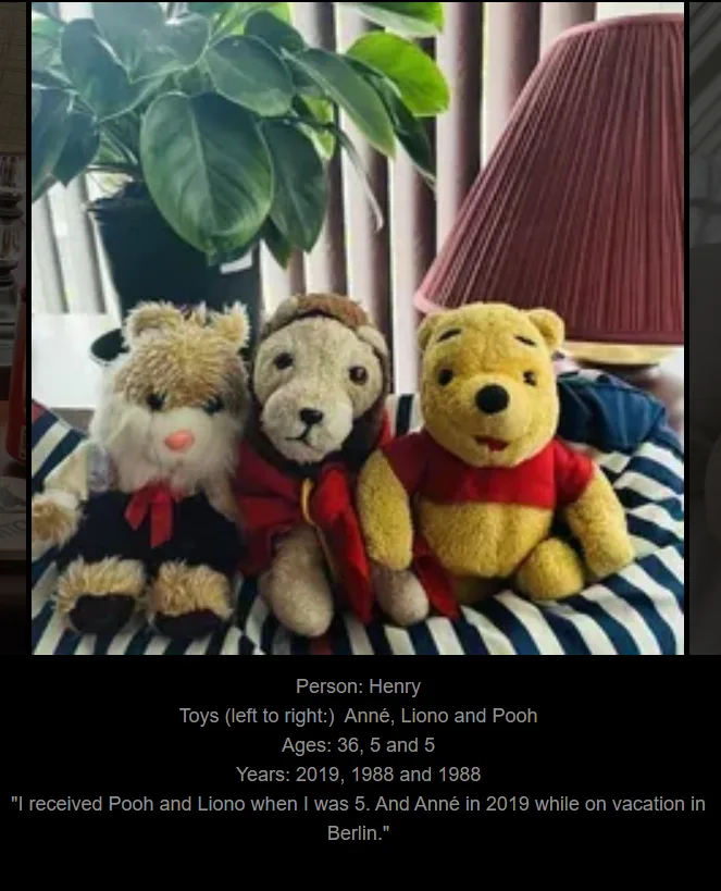 Three stuffed animals sit side-by-side on a striped surface: a shaggy brown bear, a lion in a red cape, and Winnie the Pooh…