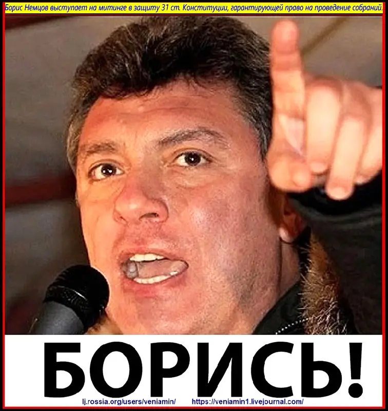 A close-up photo of a man speaking into a microphone, pointing his index finger forward with an intense expression. The…