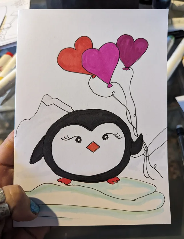 A hand holds a child's drawing of a cute, cartoon penguin with long eyelashes standing on ice, holding strings attached to…