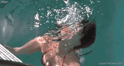 A six-panel GIF shows a woman in a red bikini emerging from turquoise water, initially submerged and gasping, then gradually…